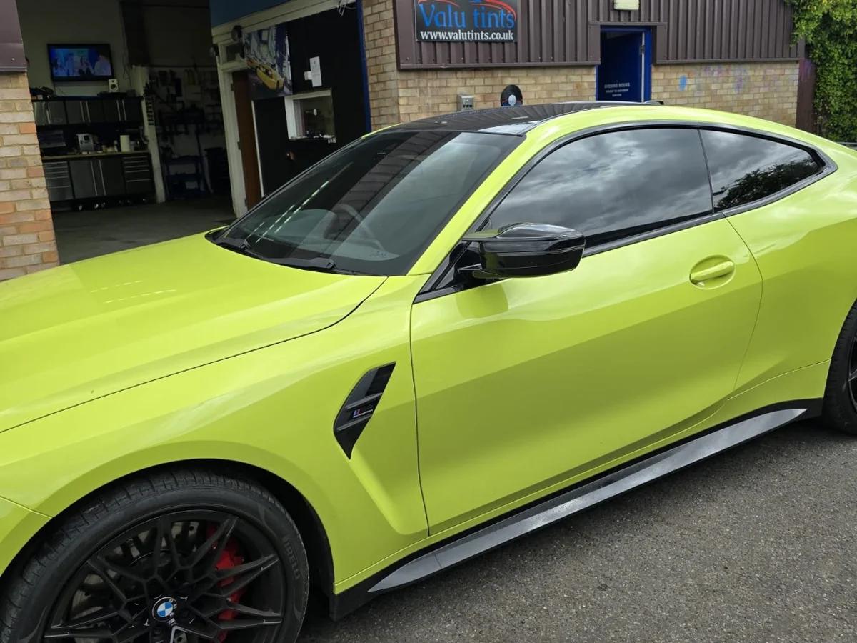 Lime green BMW with dark window tinting outside the Valu Tints workshop